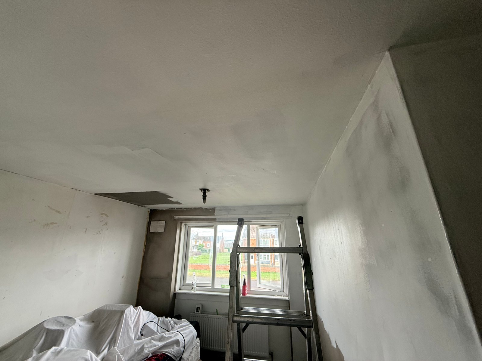 First white base coats flattening out across the fresh wall plaster