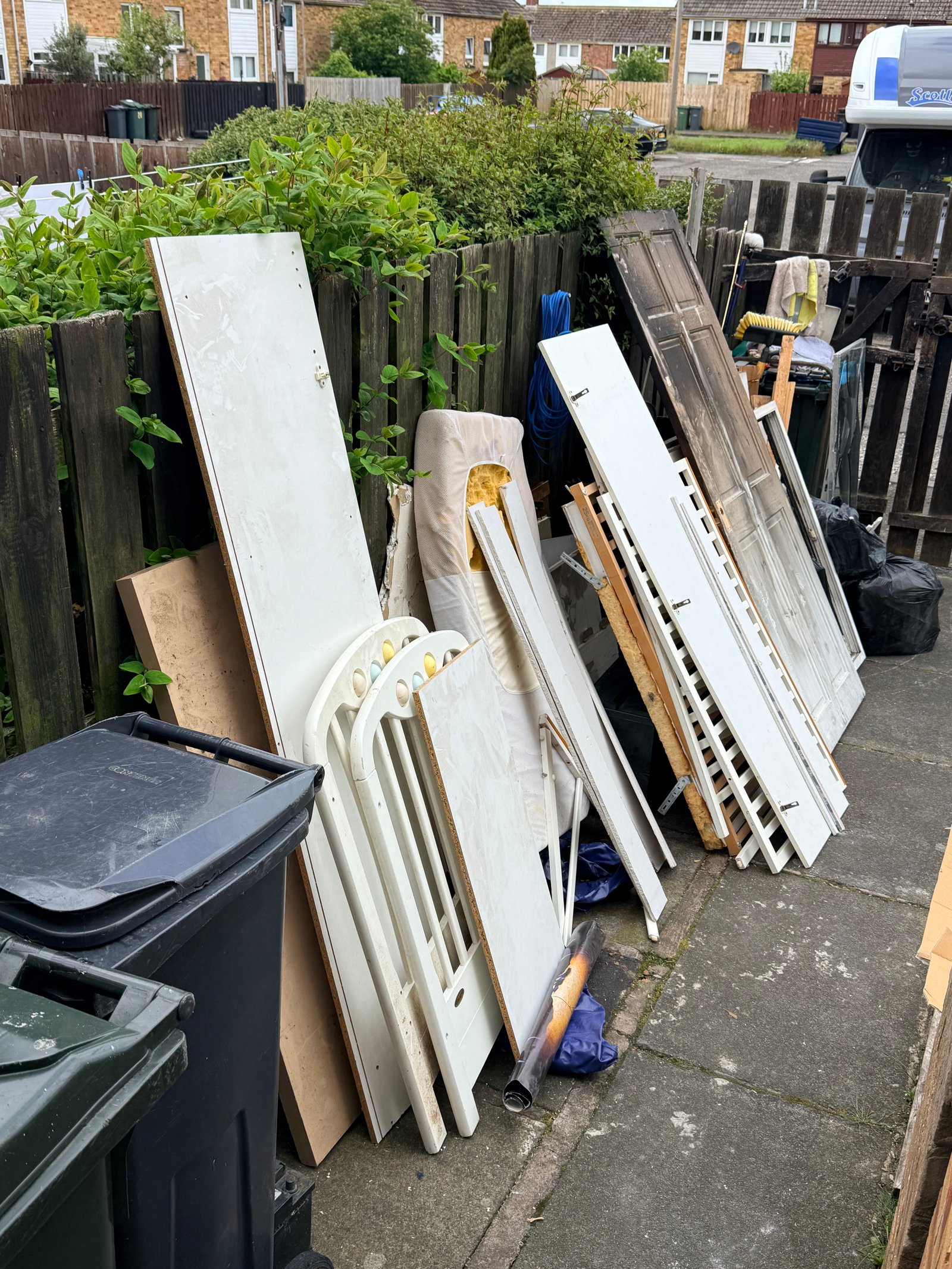 Old doors and white panels stacked by the fence
